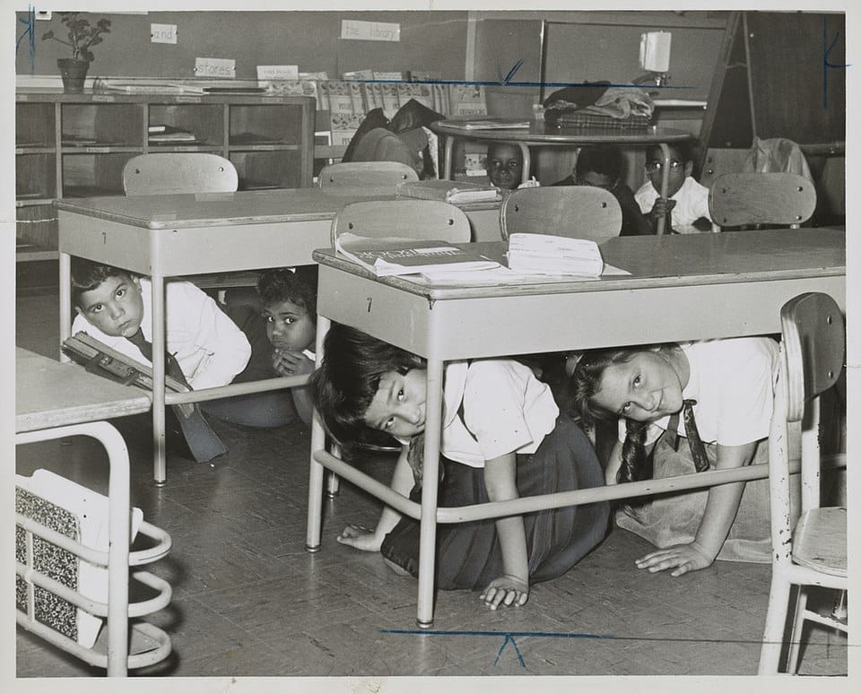 Children under desks practicing a cold war take-cover drill, 1962, Brooklyn