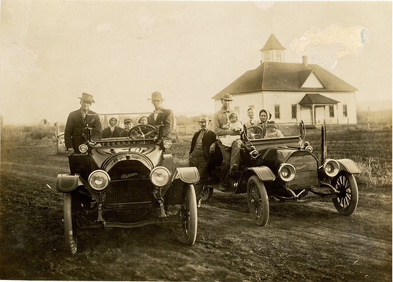 Two family groups (extended Gill members) pose inside two new Studebaker cars on a dirt road.