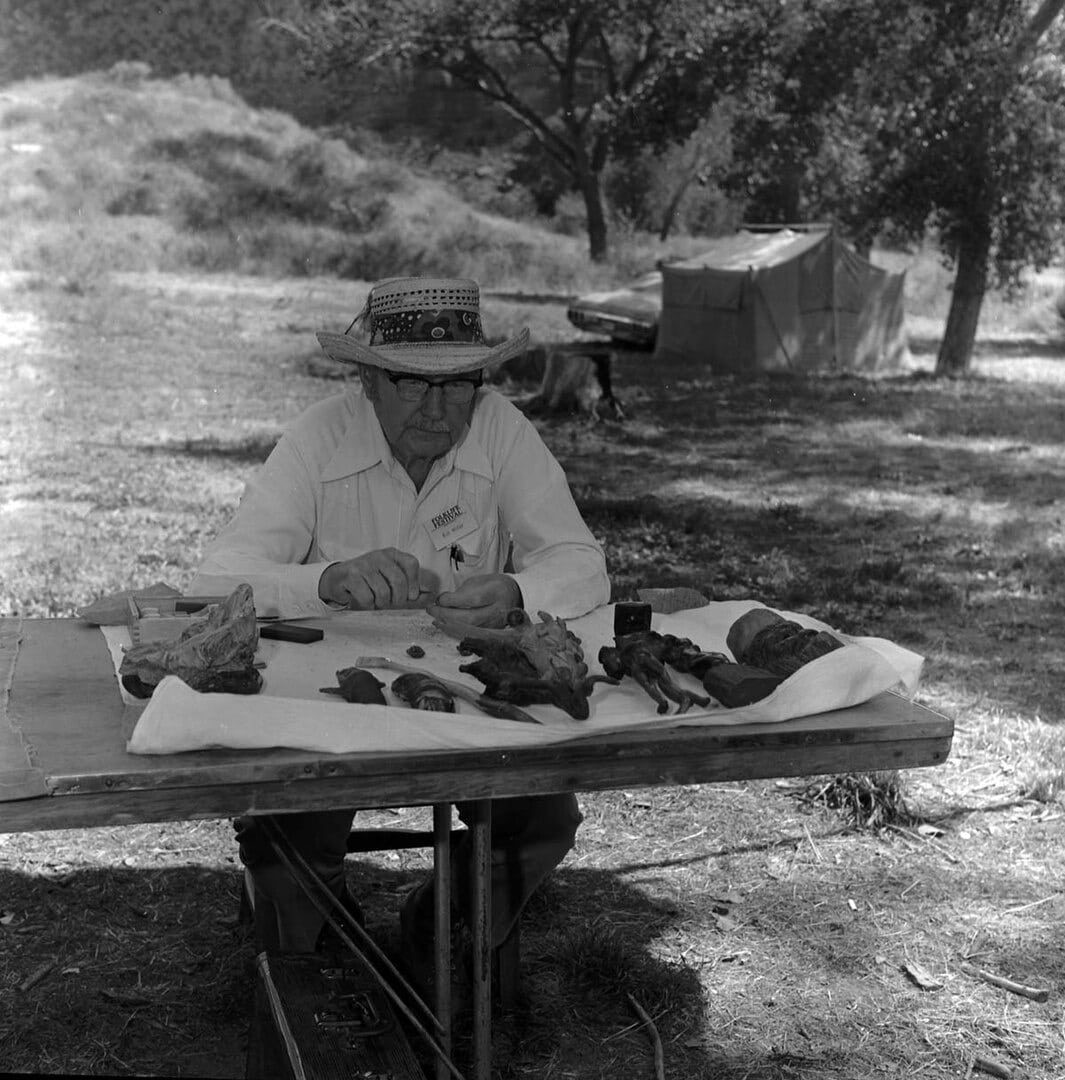 Bill Miller carving peach pit creature at Zion Folklife Festival, 1977