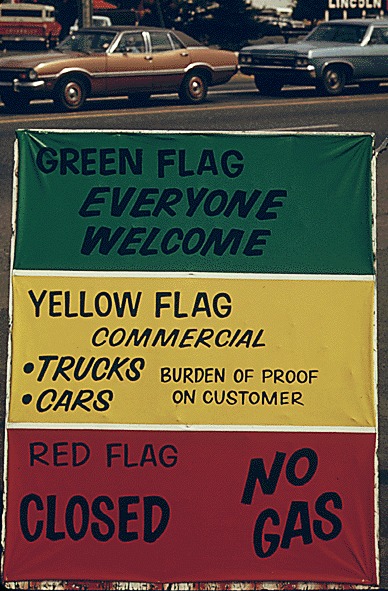 Gasoline dealers in Oregon displayed signs explaining the flag policy during the fuel crisis in the winter of 1973-74. As the sign says, the green flag means anyone can get gas, the yellow is for commercial vehicles only and a red flag means no gas at all. (May 1974)