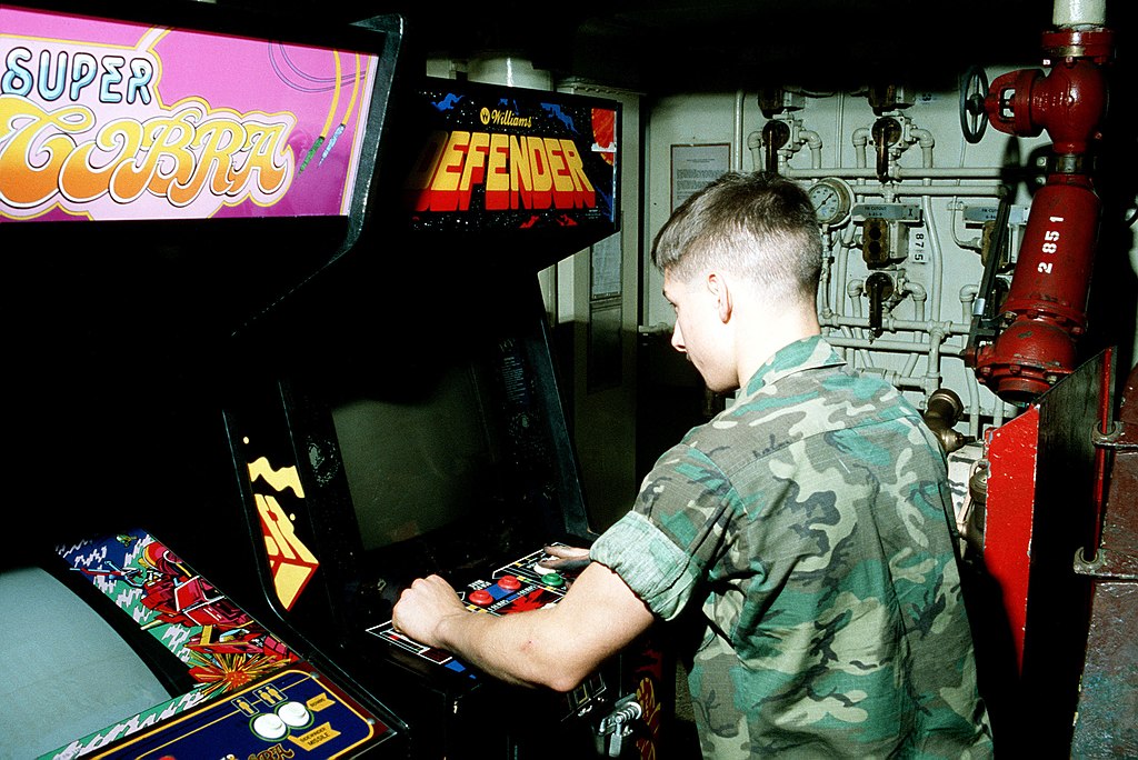 A Marine spends some of his spare time playing a video game in the game room on the aircraft carrier USS AMERICA (CV 66)- 23 August 1982