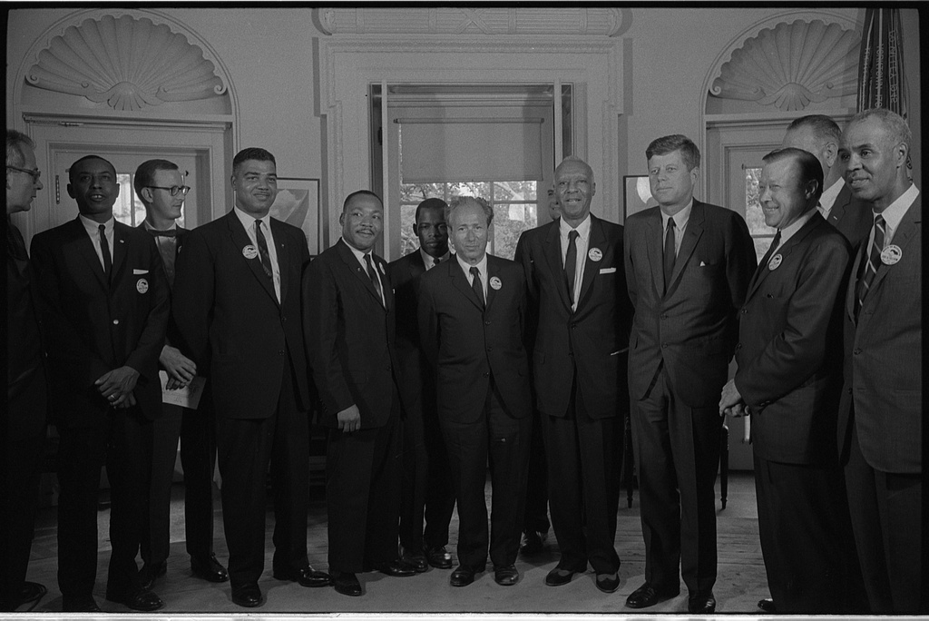 Civil rights leaders meet with President John F. Kennedy in the oval office of the White House after the March on Washington, D.C. — Photograph shows (left to right): Willard Wirtz (Secretary of Labor); Floyd McKissick (CORE); Mathew Ahmann (National Catholic Conference for Interracial Justice); Whitney Young (National Urban Leage); Martin Luther King, Jr.(SCLC); John Lewis (SNCC); Rabbi Joachim Prinz (American Jewish Congress); A. Philip Randolph, with Reverend Eugene Carson Blake partially visible behind him; President John F. Kennedy; Walter Reuther (labor leader), with Vice President Llyndon Johnson partially visible behind him; and Roy Wilkins (1963 Aug. 28)