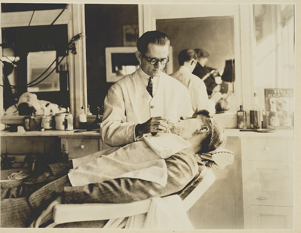 The barber- Photograph shows barber shaving a man's face. (circa 1923 March 5)