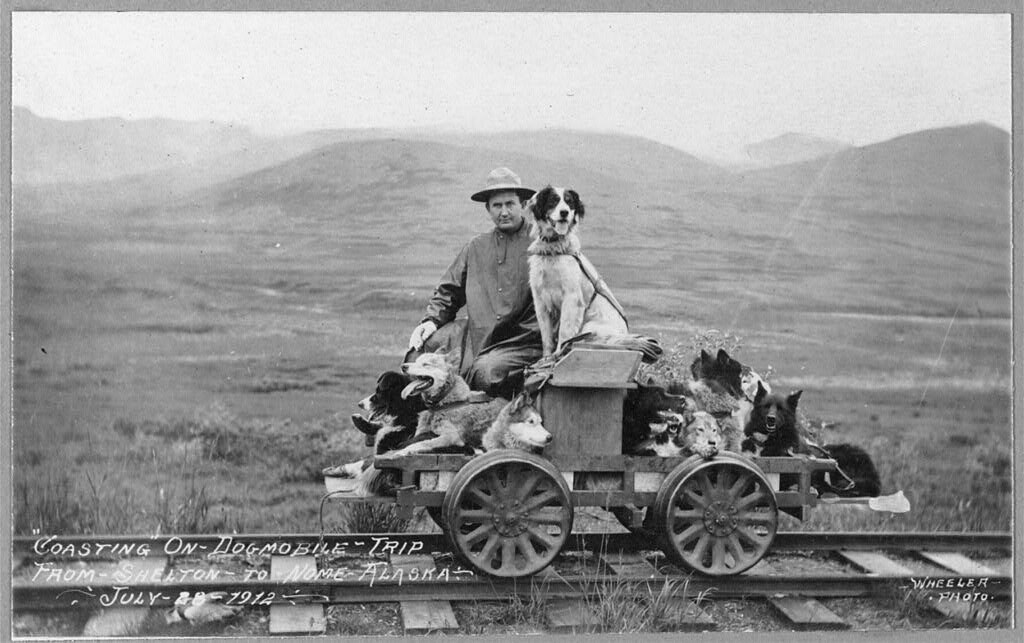 Man and dogs on rail cart (pupmobile) from Shelton to Nome (1912 July 28)