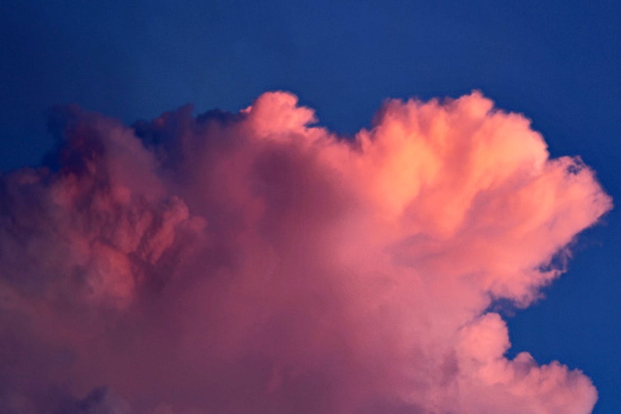 Pink cloud under clear blue sky.