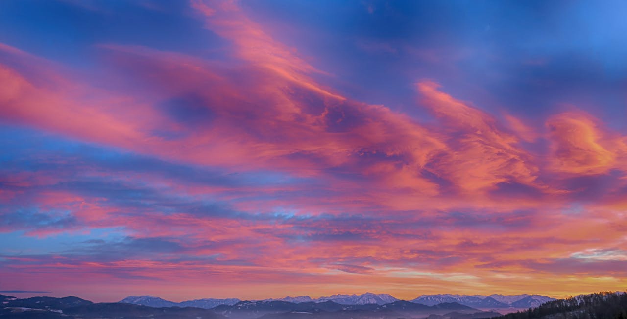 Mountains at sunset with orange clouds.