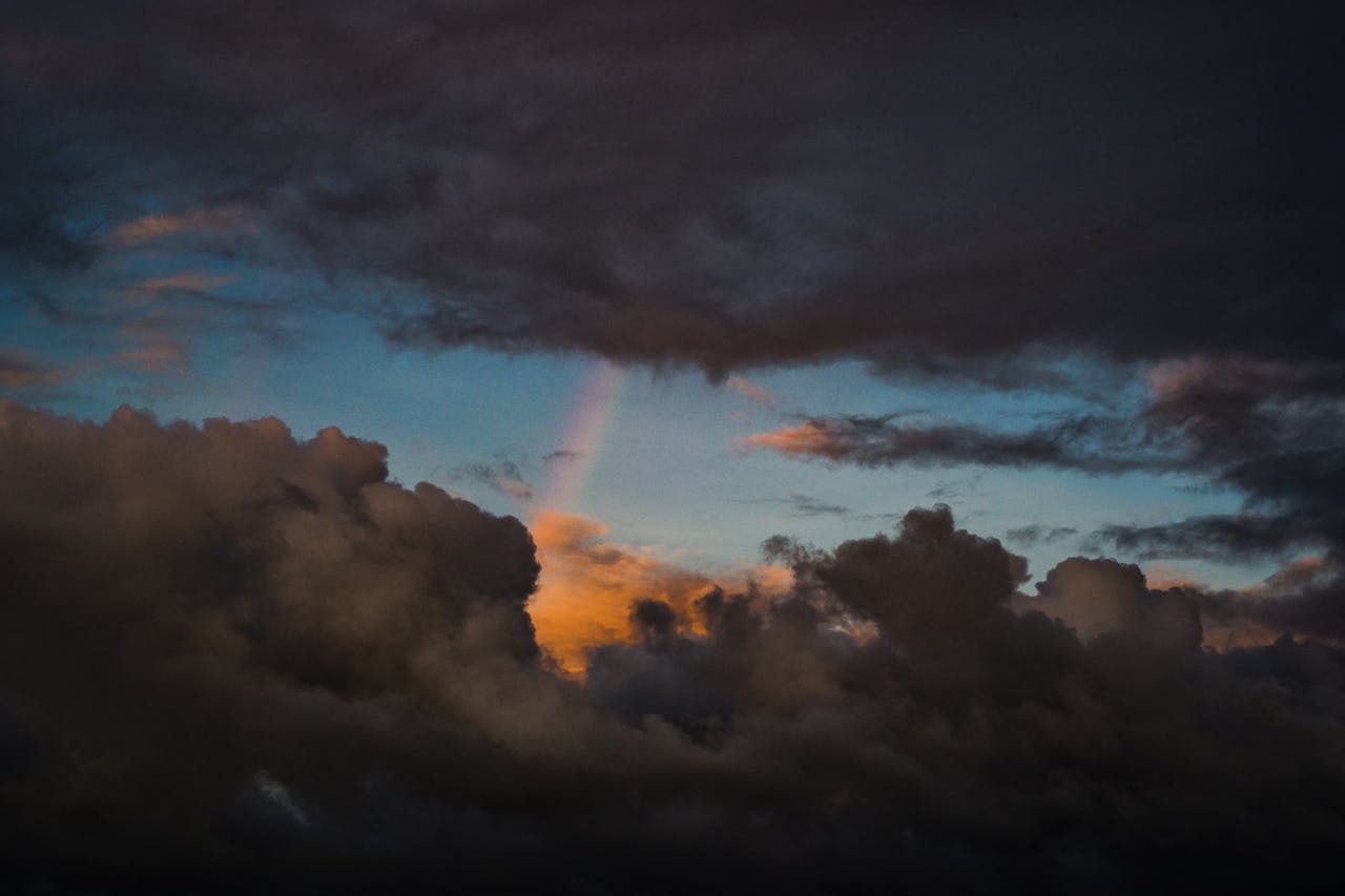 Clouds with rainbow above island.