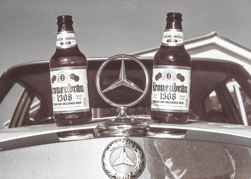 two bottles of golden oak mellowed beer on top of a Mercedes Benz