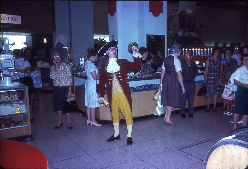 a man dressed as ancient Englishmen while holding a bell to call out customers