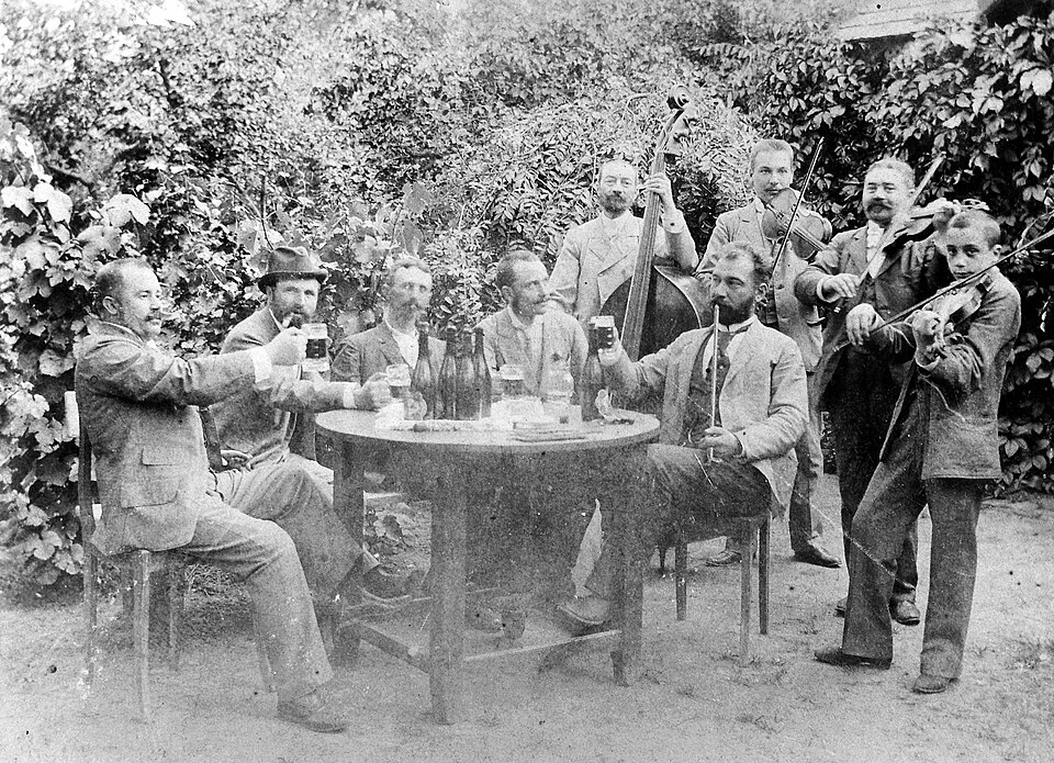 Men partying while smoking pipe with musical instruments like violin and double bass. Circa 1908