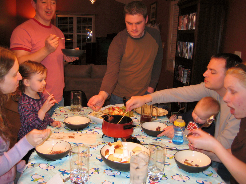 a group of family eating chocolate fondue during a home party, 2009