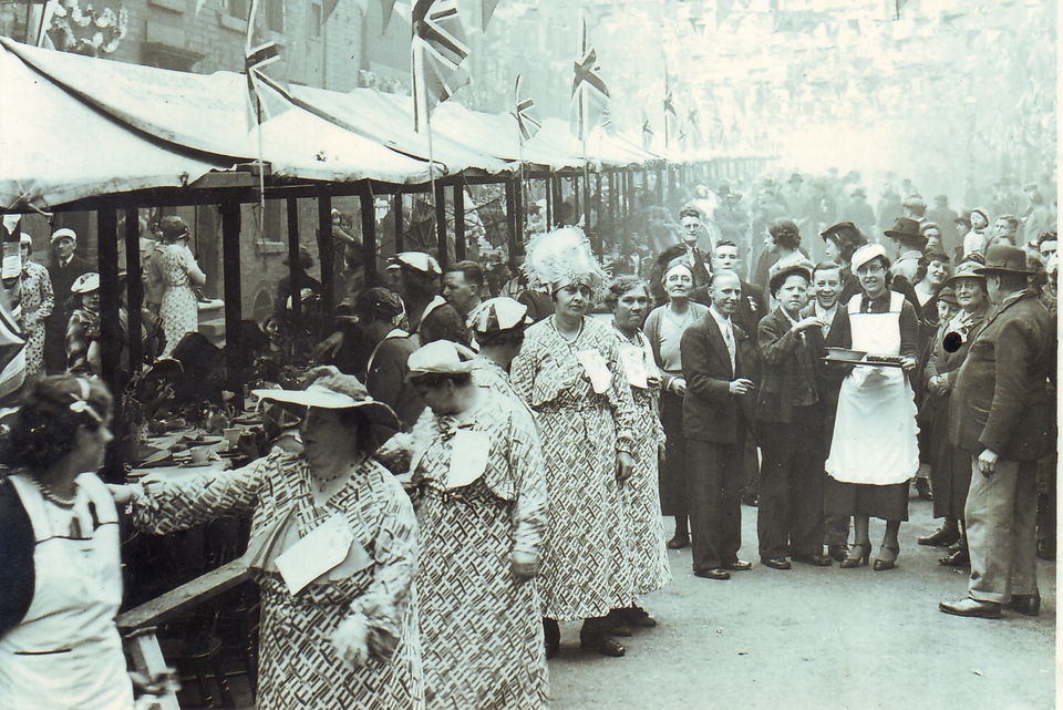 A street party in Ladywood, Birmingham. Possibly the 1937 coronation. The woman in maid's outfit carrying a tray, is Florrie Mabbett (later Florrie Jones). The woman four to her right is Fanny Mabbett (née Dorsett), her mother. Fanny was the second wife of Matthew George Mabbett, the uploader's great-grandfather.