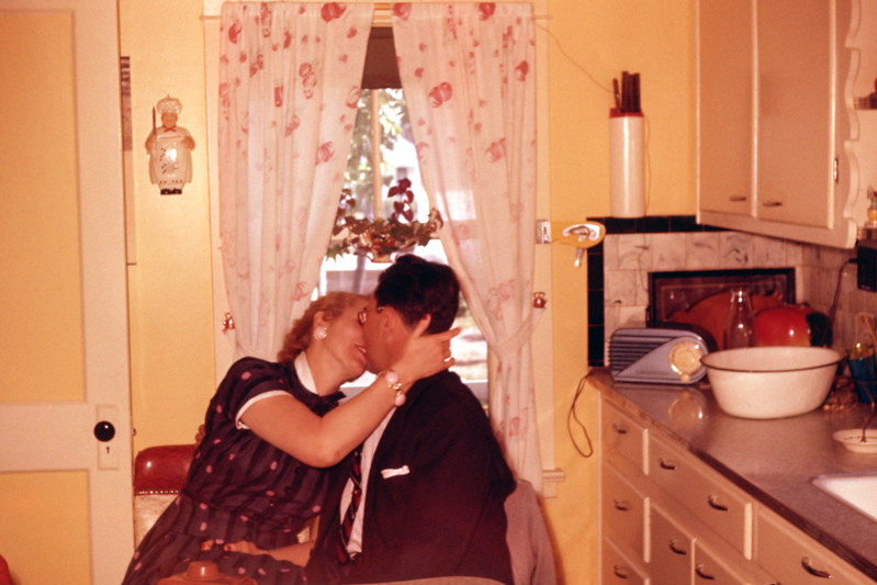 Old couple kissing in kitchen, 1950s