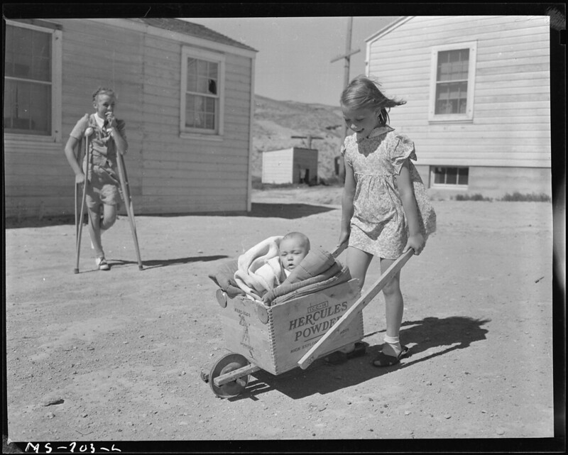 Children play with a homemade baby buggy, company housing, Reliance, Wyoming.