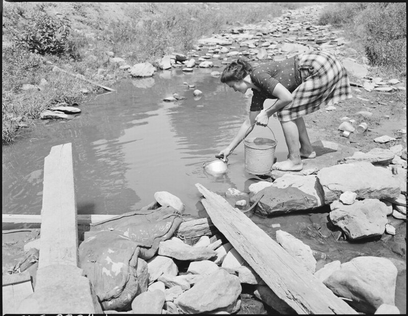 Mrs. Edna Lingar gathers water from polluted stream, Kentucky.