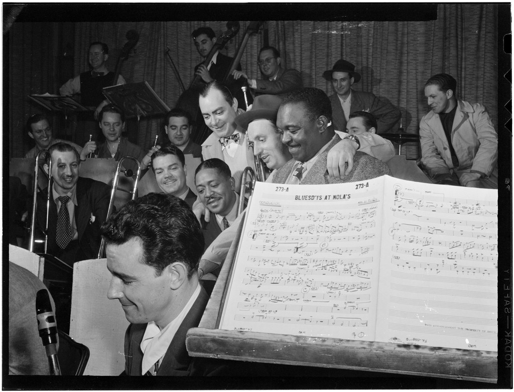 Six jazz musicians, including Brick Fleagle and Rex Stewart, grouped beside a music stand at Nola's, New York, 1947